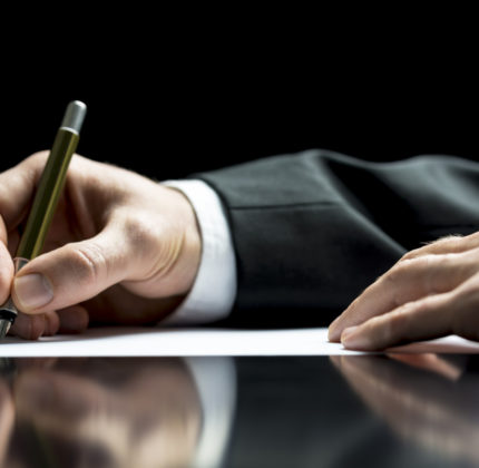 Businessman writing a letter, notes or correspondence or signing a document or agreement, close up view of his hand and the paper